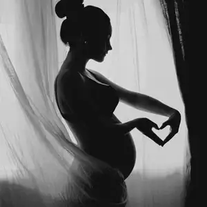 Gravid kvinde i profil der danner et hjerte med hænderne omkring maven.