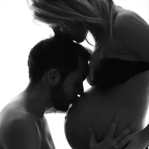 Kærligt par hvor manden kysser den gravide kvindes mave.
